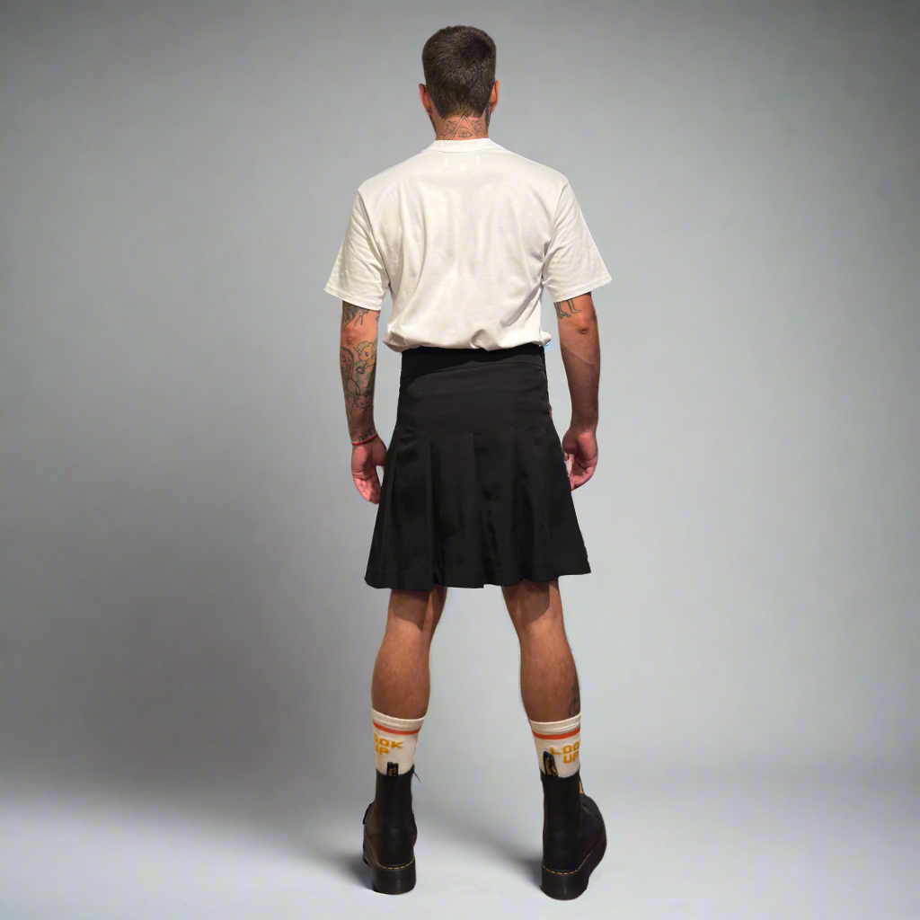 Person wearing a black kilt on a gray background