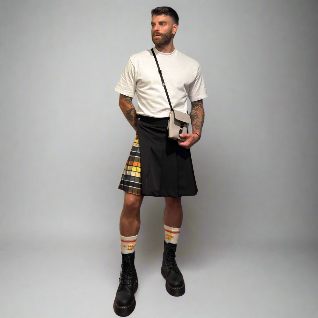 Man wearing a black kilt with plaid accents on a plain background