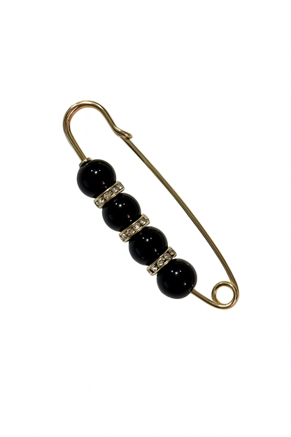 Safety pin with black beads and gold metal on a white background