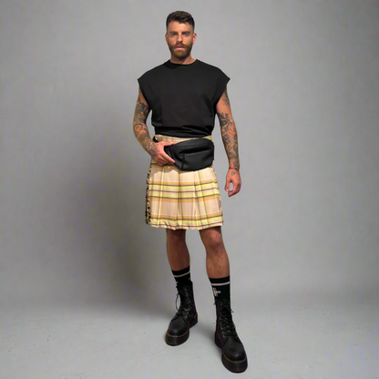 Man wearing a beige plaid kilt with black boots on a gray background