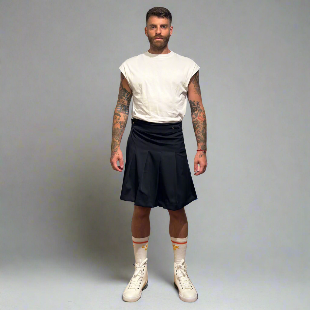 Man wearing a white t-shirt, navy kilt, and white sneakers on a gray background