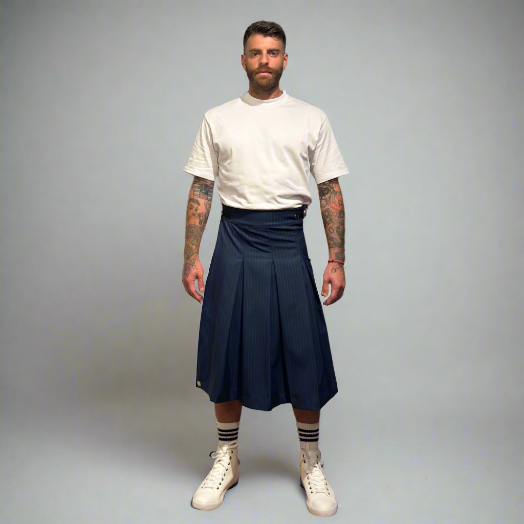 Man wearing a white t-shirt, navy kilt, and white sneakers on a gray background