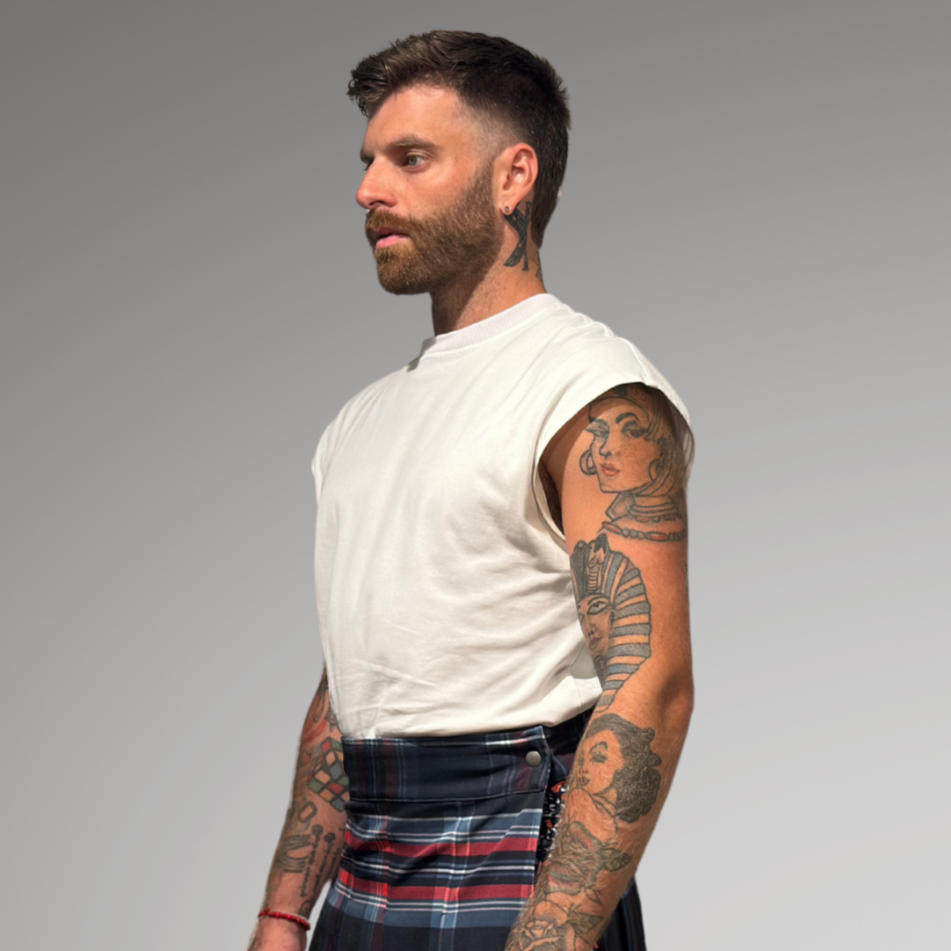 Man wearing a white sleeveless shirt and plaid kilt on a gray background