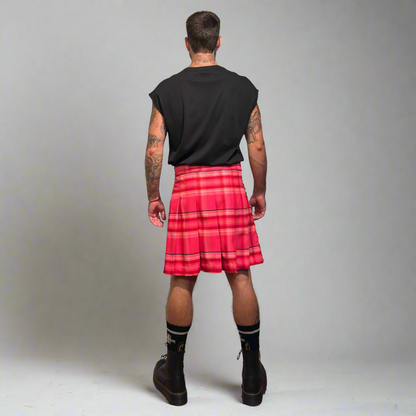 Person wearing a pink plaid kilt on a plain background